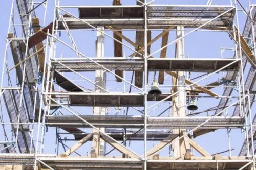 Immagine di un ponteggio su un campanile, usato per la manutenzione e la conservazione di monumenti storici.